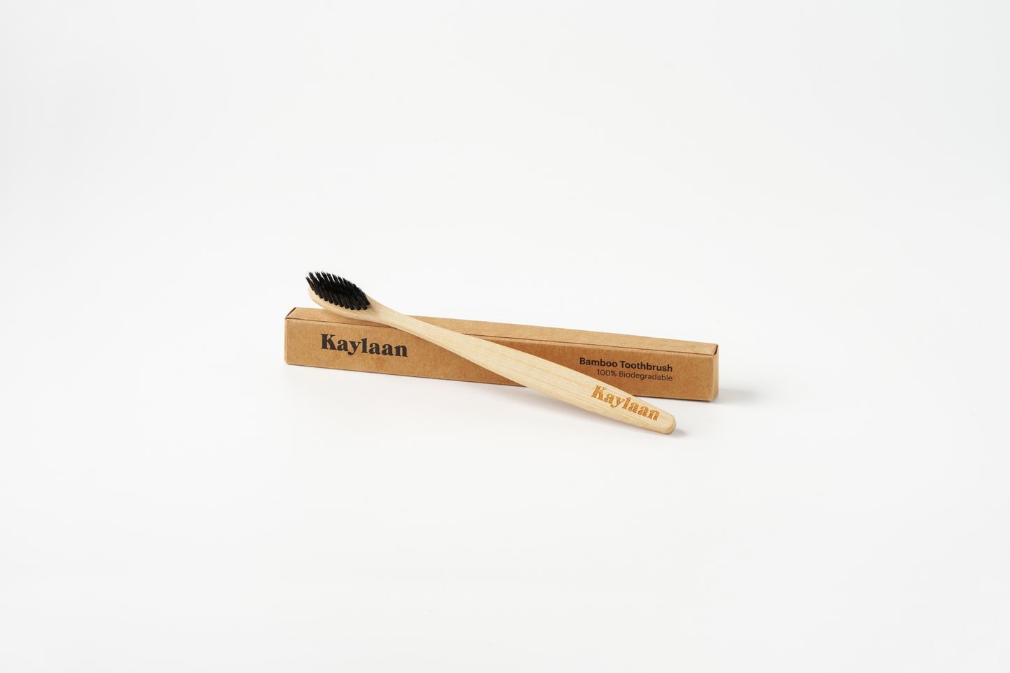 Bamboo toothbrush with black bristles in a wooden holder on a white background