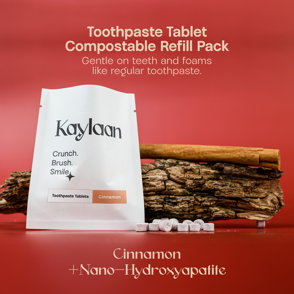 Eco-friendly Kaylaan cinnamon toothpaste tablets in a tin with cinnamon flavor, presented on a rustic wooden backdrop with compostable packaging.