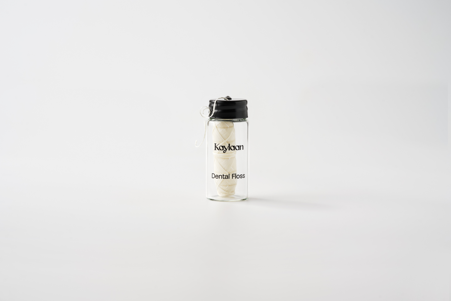 Small container with floss labeled 'Kaylaan' on a white background