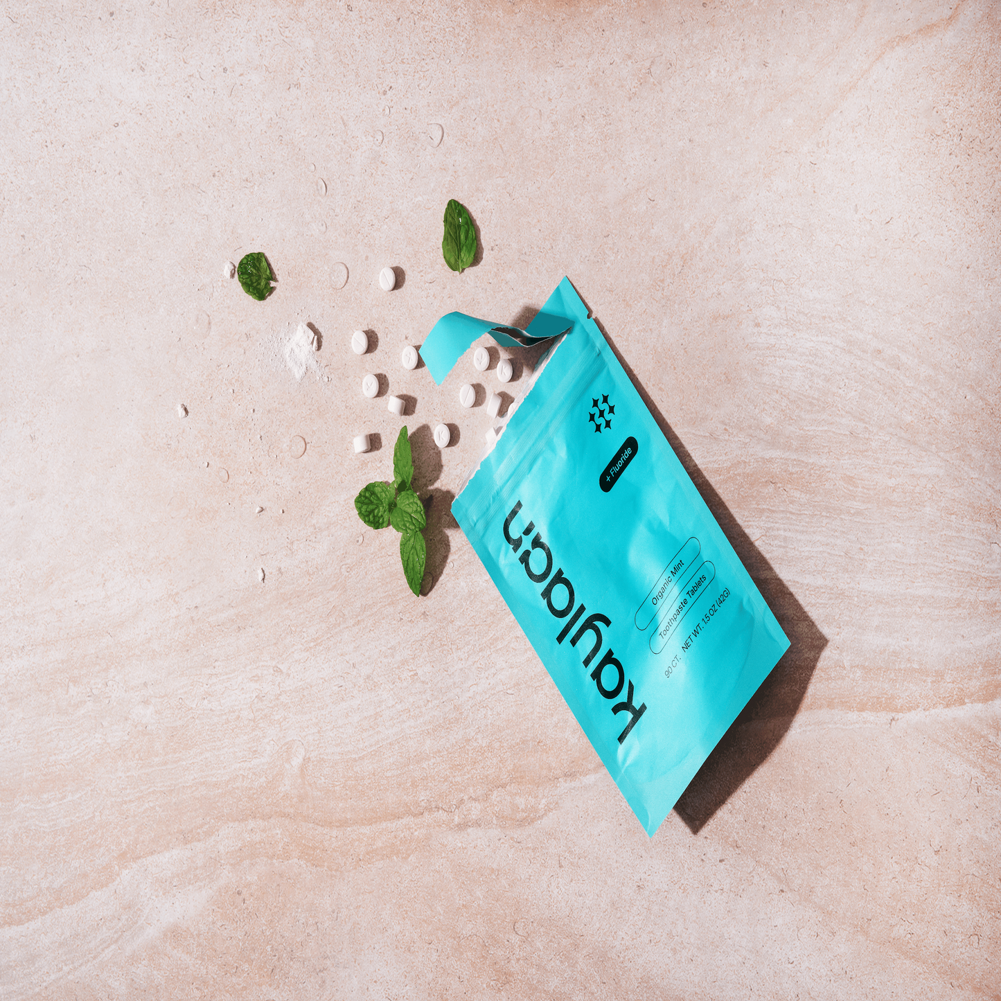 Kaylaan mint toothpaste tablets with fluoride compostable refill pouch pack poured on stone surface