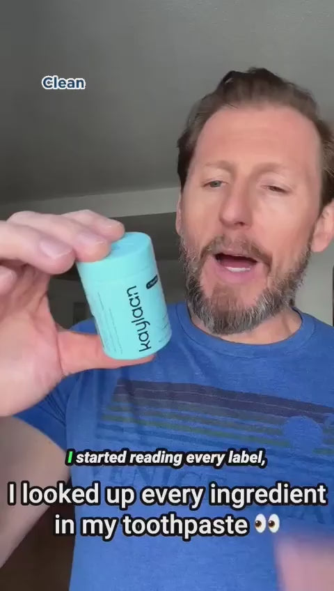 A man with a beard holding up a light blue container of Kaylaan toothpaste tablets, with text overlays reading 'Clean' and 'I started reading every label, I looked up every ingredient in my toothpaste